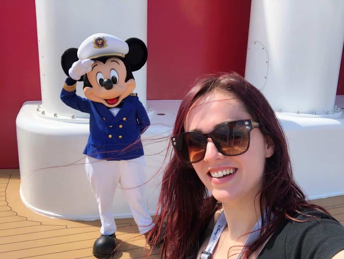 A woman in sunglasses smiles for a selfie with Captain Mickey Mouse, creating a cherished Disney Cruise Line memory during the special Covid-era character experiences.