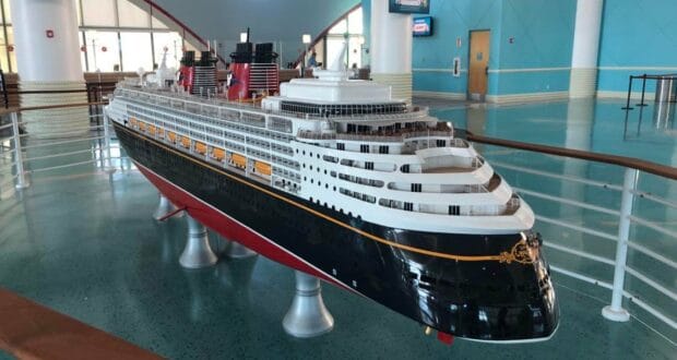 A showcase of a Disney Cruise Line ship model sits inside a themed exhibit with expansive windows and vibrant blue walls, reflecting Disney’s renowned attention to design detail and commitment to guest safety.