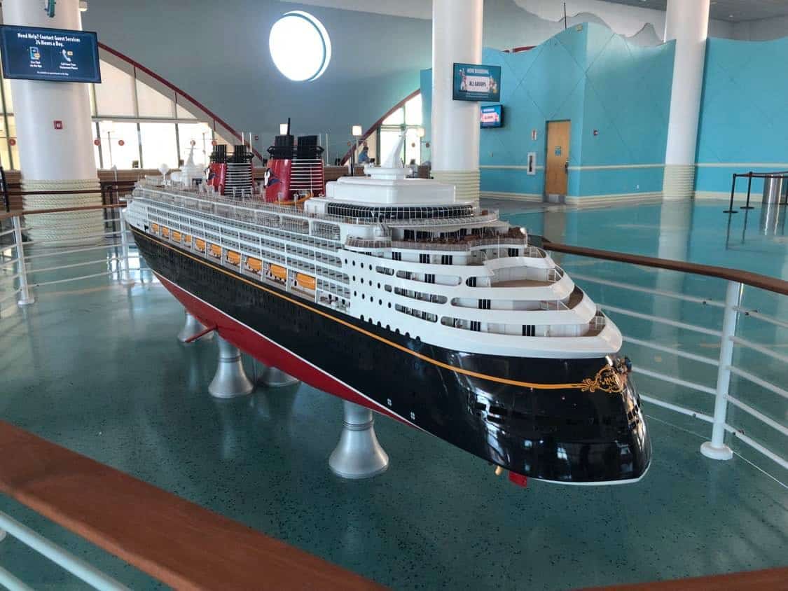 A showcase of a Disney Cruise Line ship model sits inside a themed exhibit with expansive windows and vibrant blue walls, reflecting Disney’s renowned attention to design detail and commitment to guest safety.