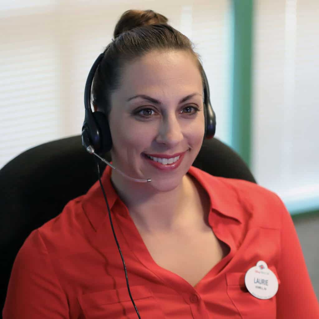 Cast Member in a bright red shirt and headset, smiling at her desk with a visible name tag, embodying the welcoming and professional Disney spirit that guests experience at Walt Disney World.