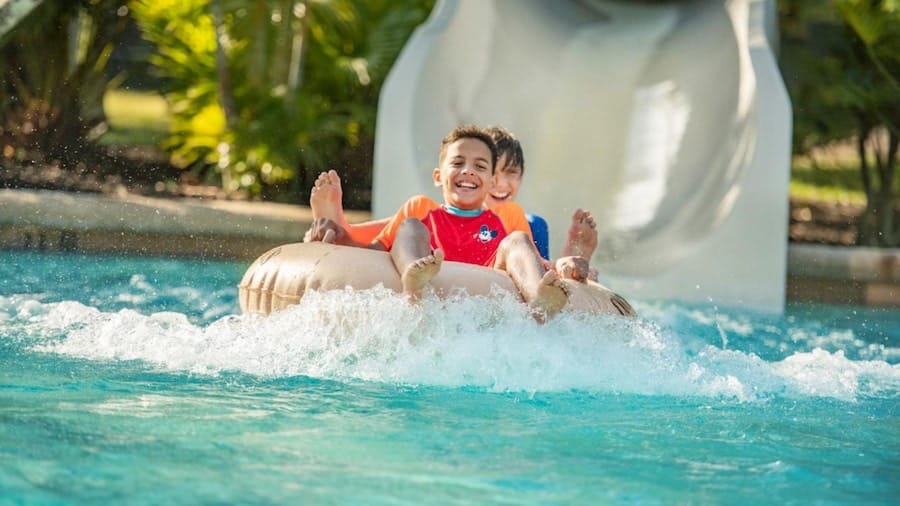 Kids laugh with excitement as their raft whooshes down a swirling water slide into a splashy pool at Typhoon Lagoon, Disney’s thrilling water adventure park.