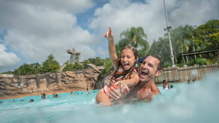 Guests enjoy the waves at Disney’s Typhoon Lagoon, with palm trees and fellow visitors creating the perfect backdrop for a sunny day of water park fun.