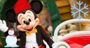 Mickey Mouse sporting a festive red hat waves beside a red car at Disney World, with playful snowman and snowflake graphics added to announce chilly weather heading to Central Florida.