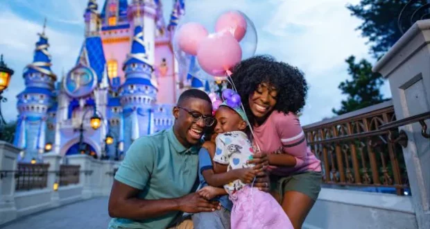 A Florida resident family beams with joy in front of Cinderella Castle at Walt Disney World, holding iconic pink Mickey Mouse balloons and celebrating their special ticket discounts for locals.