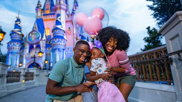 A Florida resident family beams with joy in front of Cinderella Castle at Walt Disney World, holding iconic pink Mickey Mouse balloons and celebrating their special ticket discounts for locals.