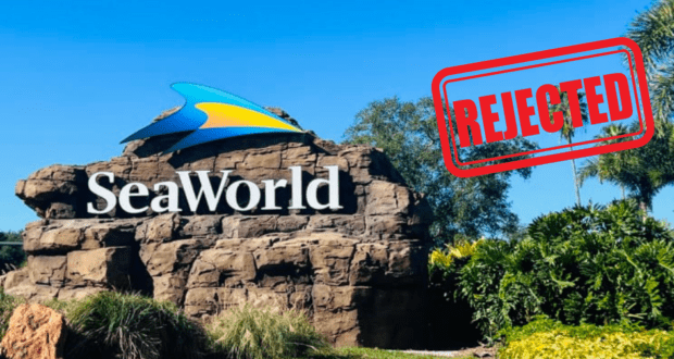 SeaWorld’s iconic entrance sign stamped boldly with “REJECTED” in red, framed by lush landscaping and a bright blue sky—reflecting the buzzworthy news that SeaWorld has declined a multi-billion dollar takeover bid.