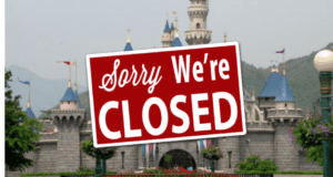 A "Sorry, We're Closed" sign stands in front of Cinderella Castle at Disneyland, capturing fans' disappointment as the park announces another extended closure.