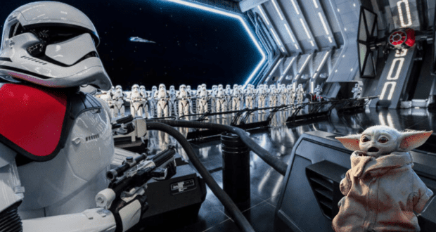 Grogu (Baby Yoda) stands in front of a formation of stormtroopers inside a Star Wars: Galaxy’s Edge spaceship hangar—can you wait in line as long as fellow fans for Star Wars: Rise of the Resistance at Disneyland?.