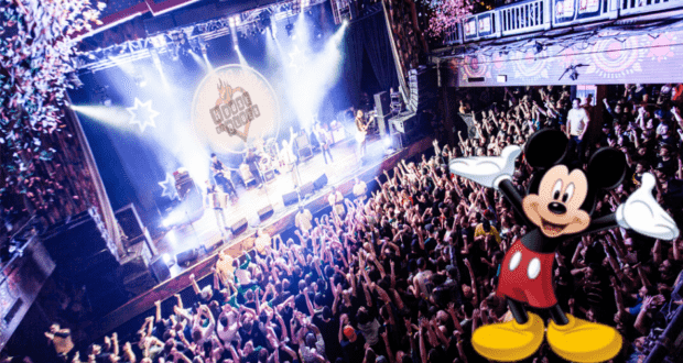 Mickey Mouse welcomes fans in front of a vibrant concert crowd and dazzling stage lights indoors, joining the excitement as live music and tours make their big return—better than ever—at House of Blues Orlando.