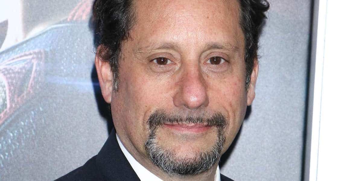 A well-dressed guest with dark hair and a goatee smiles slightly during an exclusive premiere at Universal Studios, his expression tinged with reflection after fans learned of editor David Brenner’s passing at 59.