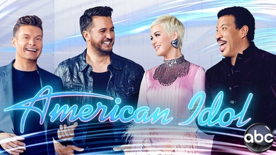 The four smiling American Idol hosts gather in front of a vibrant blue and white backdrop, where the iconic ABC logo joins sparkling Disney touches, capturing the thrilling blend of American Idol excitement with classic Disney enchantment that fans love.