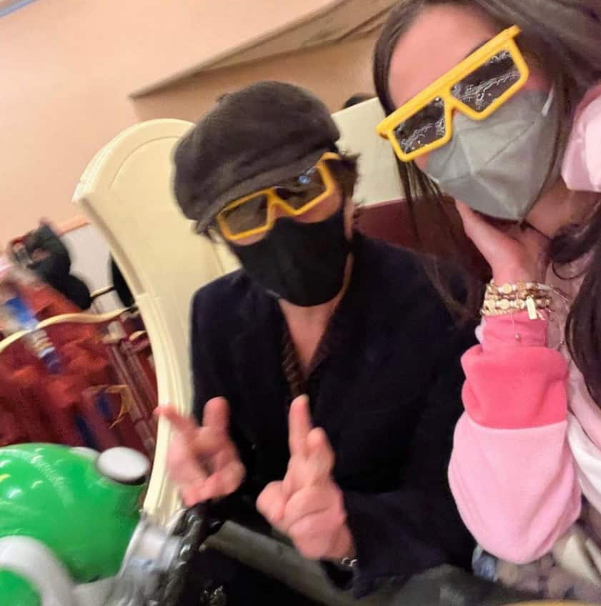 Guests in masks and 3D glasses snap a selfie while enjoying a park ride, capturing playful Disney vibes reminiscent of John Stamos’s iconic dress-up moments.