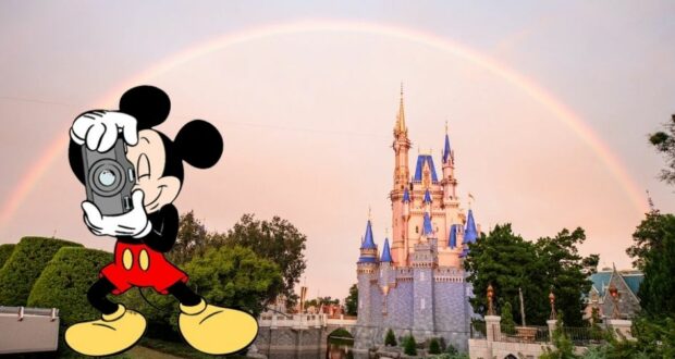 Mickey Mouse snaps a photo of the iconic Disney castle beneath a radiant rainbow at Disney World, capturing the kind of enchanting moment that embodies the magic fans love.