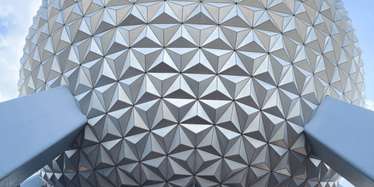 Close-up of EPCOT’s iconic Spaceship Earth, showing its gleaming silver triangular panels and sturdy support beams, embodying the cutting-edge design and excitement found at Disney Parks.