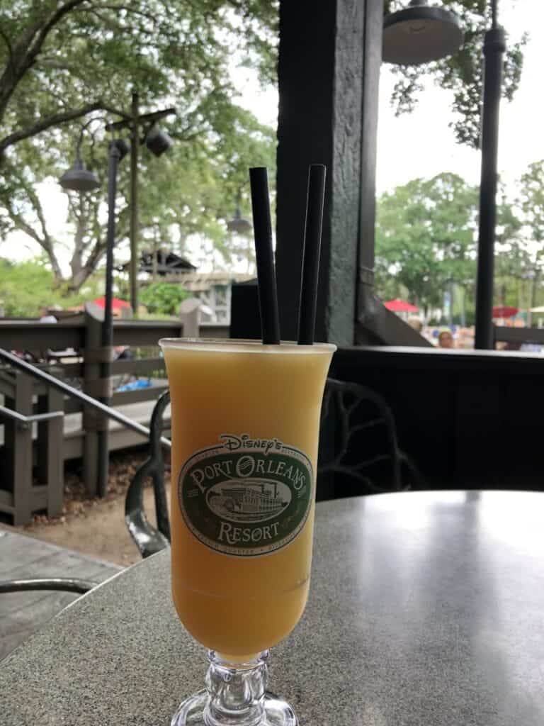 A refreshing frozen yellow cocktail with two straws sits on an outdoor table at Disney’s Port Orleans Riverside Resort, ready to be enjoyed during a magical day at the resort.