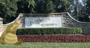 Louis the alligator greets guests with a big smile on the lush lawn in front of the iconic Port Orleans Resort Riverside entrance sign, setting a welcoming tone at this beloved Disney Resort.