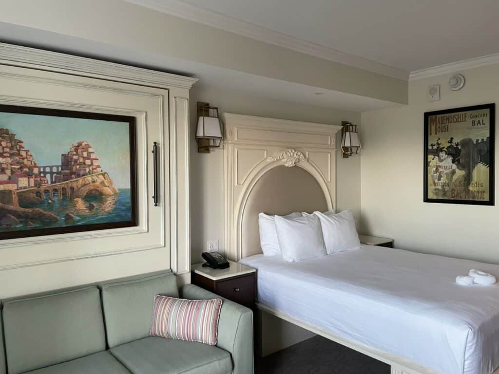 Spacious Disney Resort hotel room featuring a plush bed, vibrant green sofa, playful Disney-themed wall art, bedside tables, and warm lighting—an inviting retreat designed to enhance your magical experience after a day in the parks or as part of your Disney Vacation Club adventure.