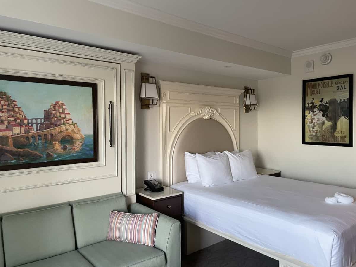 Spacious Disney Resort hotel room featuring a plush bed, vibrant green sofa, playful Disney-themed wall art, bedside tables, and warm lighting—an inviting retreat designed to enhance your magical experience after a day in the parks or as part of your Disney Vacation Club adventure.