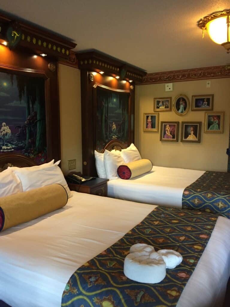 Step into the magic of Port Orleans – Riverside, where two beds with decorative pillows and a towel swan welcome guests, and Disney princess artwork brings enchanted storytelling right to your resort room.