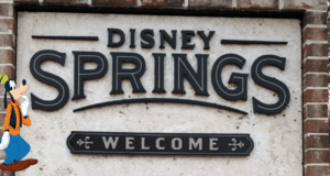 Disney Springs welcome sign displayed on a brick wall, featuring Goofy on the left, enthusiastically greeting visitors and setting the stage for an unforgettable Disney World experience.
