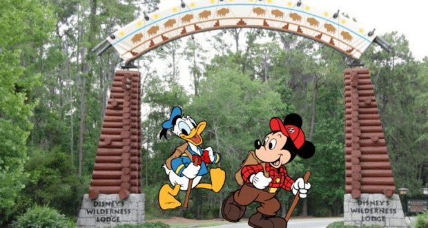 Mickey Mouse and Donald Duck, dressed in hiking gear, greet guests beneath the iconic entrance arch of Disney's Wilderness Lodge Resort.