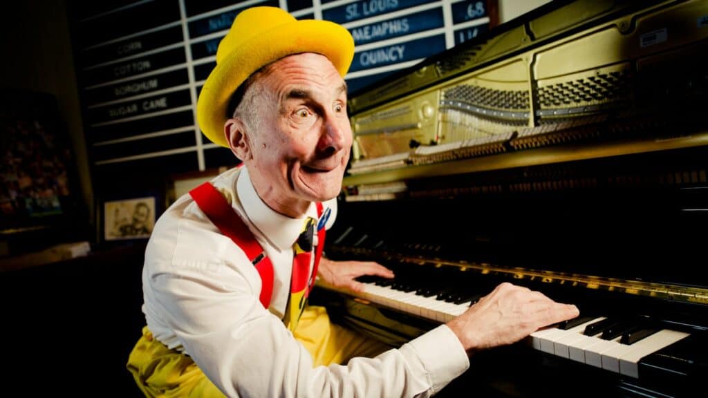 A lively pianist in a bright yellow hat and suspenders entertains guests at Port Orleans – Riverside, bringing the energetic spirit of Disney Resort to life with every playful note.