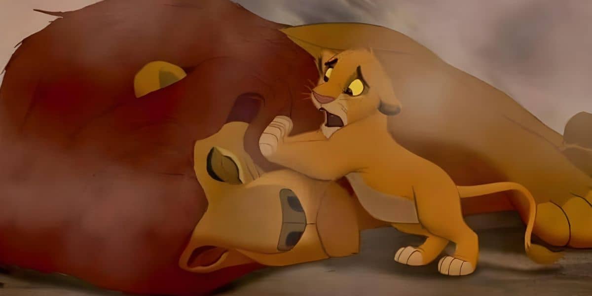 In one of the saddest Disney moments, a young animated lion cub, looking distressed, tries to rouse a larger lion lying on the ground in a dusty environment. The scene is emotionally intense as the larger lion lies unconscious.
