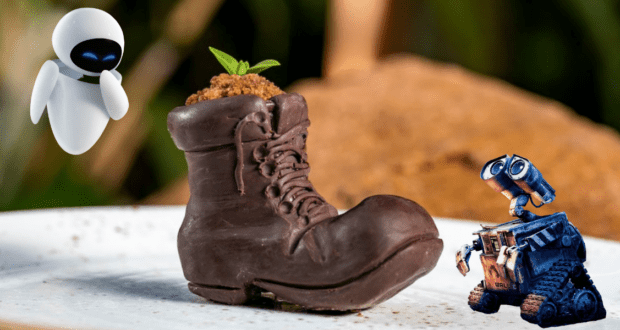 EVE and WALL-E admire the Earth Day-inspired chocolate boot snack at Disney Parks, featuring a tiny plant sprouting from the top—a whimsical treat that celebrates environmental themes with Pixar charm.
