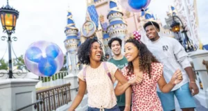 A group of friends laugh and stroll past Cinderella Castle at Disney World, holding colorful balloons as they celebrate their BoxLunch Walt Disney World Giveaway win and enjoy an unforgettable free vacation in the heart of the park’s magic.