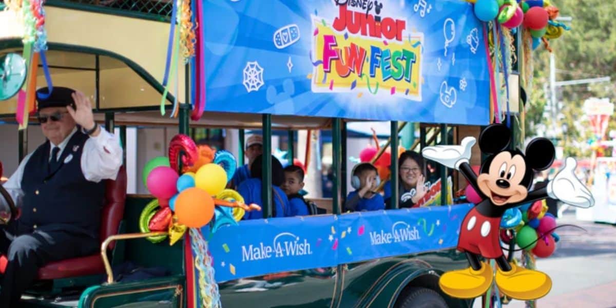 Mickey Mouse leads a vibrant Disney Junior Fun Fest parade float, surrounded by waving fans and bright balloons, spreading Disneyland magic and celebrating the dreams being fulfilled through Make-A-Wish.
