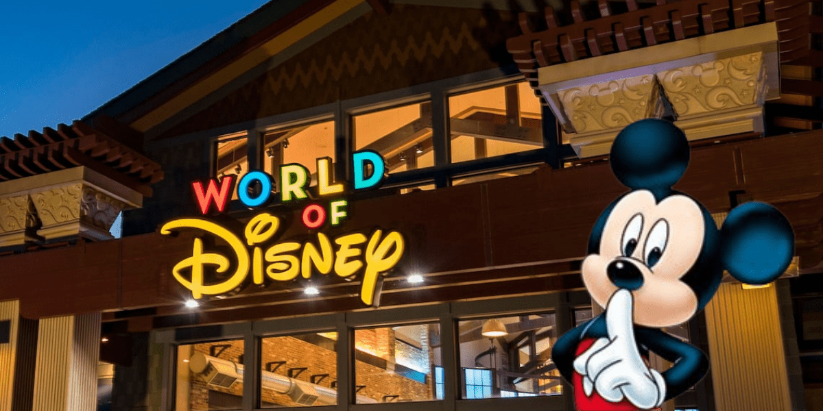 The image features the illuminated exterior of the World of Disney store at Disney Springs, with a sign above the entrance. In the foreground, a large image of Mickey Mouse playfully holds a finger to his lips, set against a dusky sky—a perfect scene for Disney shopping enthusiasts.