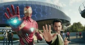 Iron Man joins a guest for a heroic photo op, both striking dynamic poses with outstretched hands in front of the high-tech Avengers Campus at Disneyland Paris.