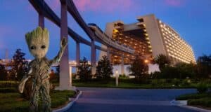 A small tree-like character waves in the foreground near a modern hotel building, part of a Disney World Deluxe Resort. A monorail track arches above, as vivid pink and blue skies hint at extended evening hours. Lush trees and landscaping beautifully wrap around the area.