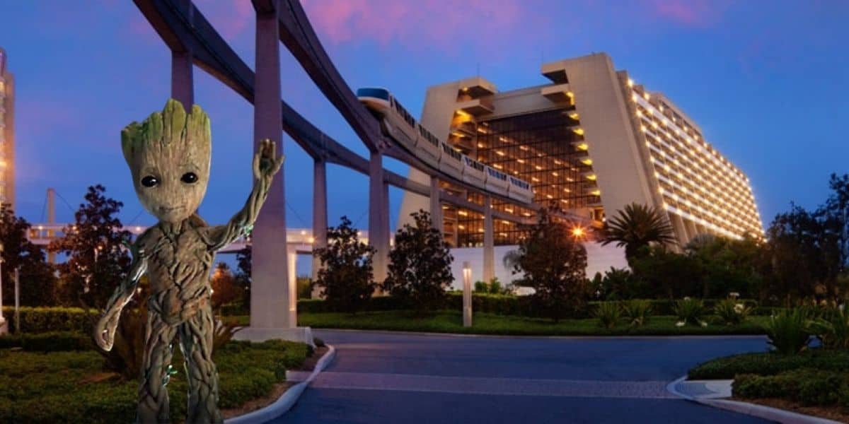A small tree-like character waves in the foreground near a modern hotel building, part of a Disney World Deluxe Resort. A monorail track arches above, as vivid pink and blue skies hint at extended evening hours. Lush trees and landscaping beautifully wrap around the area.