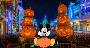 Mickey Mouse welcomes guests from atop a festive pumpkin surrounded by stacked jack-o’-lanterns, with a glowing castle illuminating the night sky—bringing the vibrant Halloween magic of Disney World to life for Mickey's Halloween Party attendees.