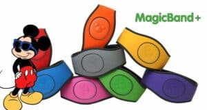Vibrant MagicBands stacked together, the MagicBand+ logo, and Mickey Mouse in sunglasses and classic red shorts on the left capture the excitement of MagicBand+ launching at Disney Parks.
