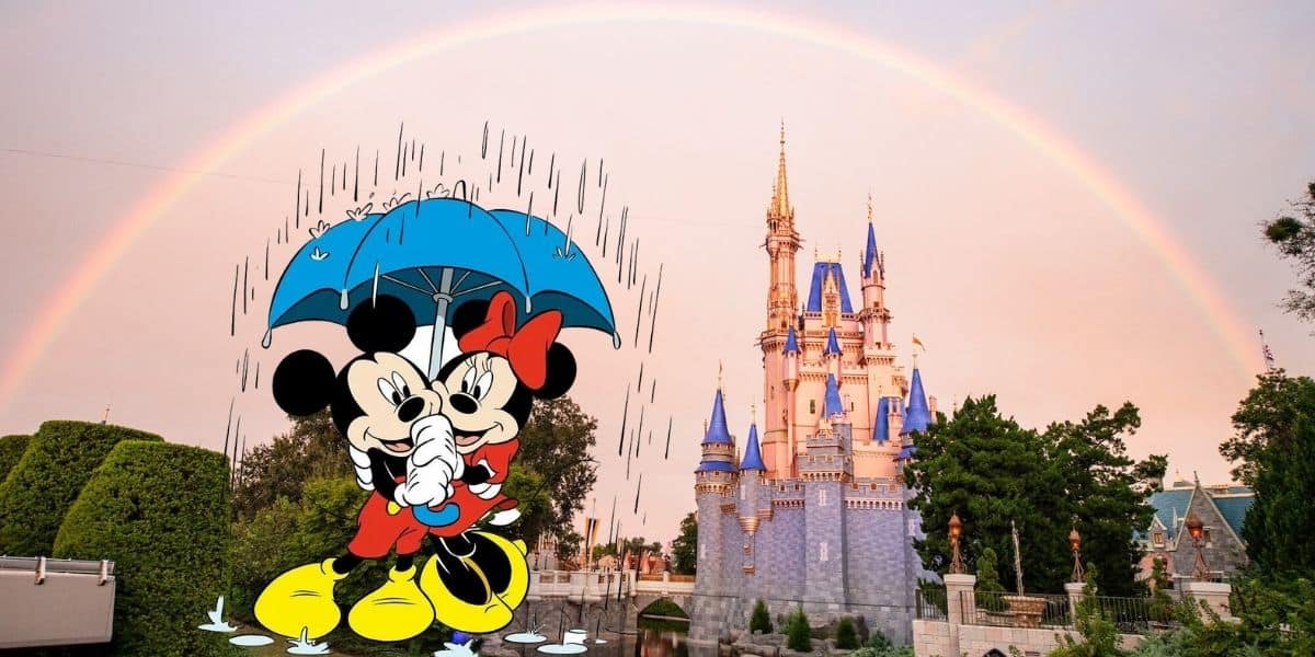 Minnie and Mickey Mouse stand under a blue umbrella with rain falling on them, in front of a castle with blue rooftops and a bright rainbow arching across the sky, capturing the magical weather at Disney World.