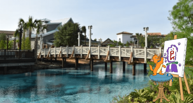 A charming Disney bear brings creativity to life, painting at an easel beside the sparkling turquoise lake at Disney Springs. Guests can spot the iconic wooden bridge and vibrant shops in the background, all part of the bustling Art Walk experience.