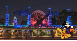 Disney California Adventure shimmers under Halloween lights at night, with Mickey Mouse and Pluto—each holding pumpkin buckets—welcoming guests to the lively Oogie Boogie Bash celebration.