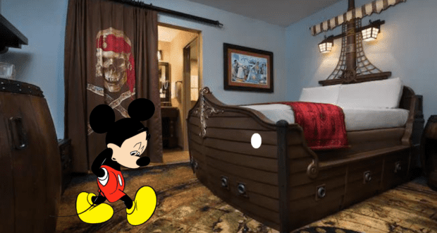Mickey Mouse looks forlorn as he stands in a pirate-themed Disney resort room, surrounded by adventurous Pirate Room details like a ship-shaped bed and swashbuckling décor inspired by Disney’s Caribbean Beach Resort.