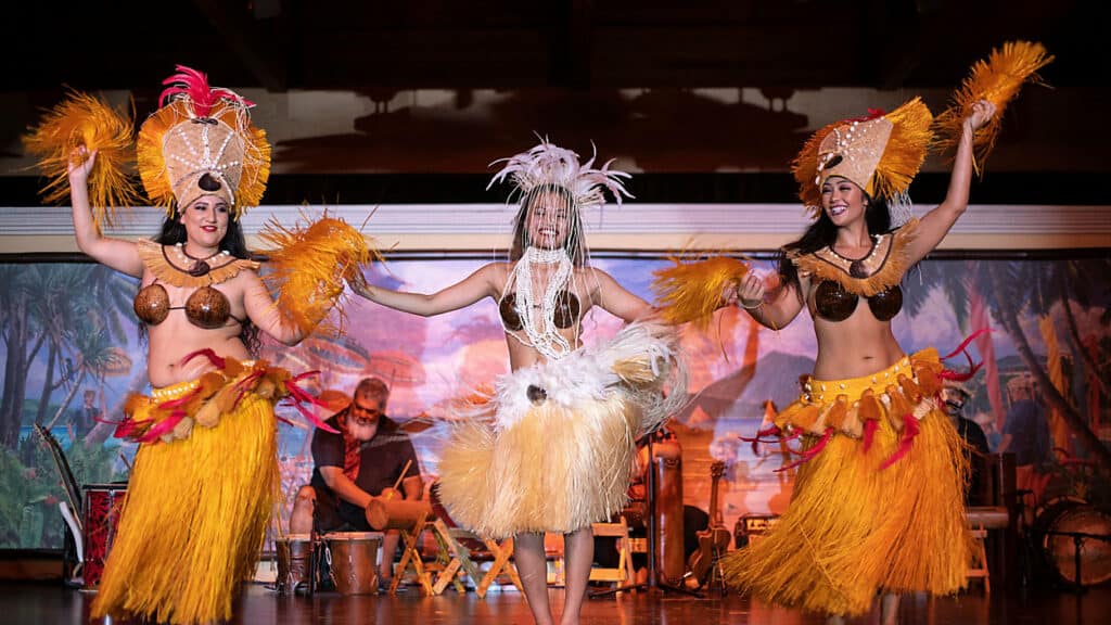 Dancers in colorful grass skirts and headdresses light up the stage at Universal Orlando’s Wantilan Luau, moving to Polynesian rhythms with a tropical backdrop, showcasing the dynamic energy that makes this dinner show stand out from Disney’s Spirit of Aloha.