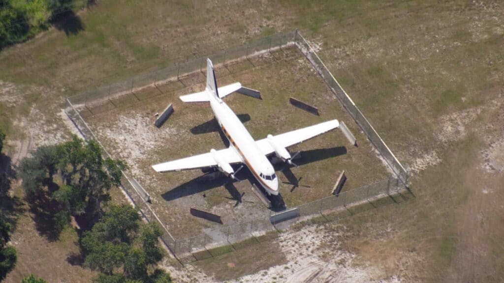 Walt's iconic airplane, featured at D23 Expo, rests inside a fenced area on the grass, seen from above like a behind-the-scenes glimpse into Disney history.