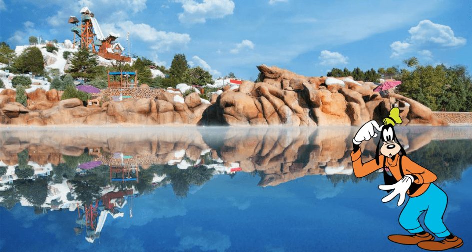 Goofy greets guests beside a shimmering pool at Disney's Blizzard Beach, set against the backdrop of thrilling water slides and snow-capped rock formations.