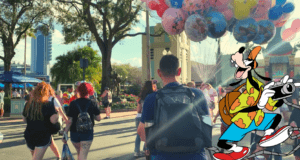 Disney World buzzes with energy as families stroll past cheerful balloons, while Goofy snaps photos in the foreground—showcasing must-have Disney backpack essentials for a magical day of fun and adventure.