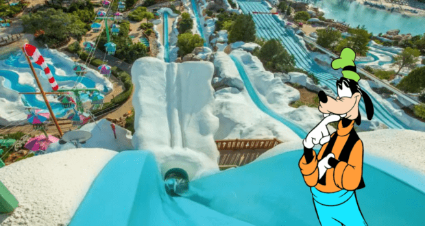 Goofy greets guests beside the iconic winding water slide at Disney’s Blizzard Beach, surrounded by vibrant summer fun as the beloved water park reopens under sunny skies.