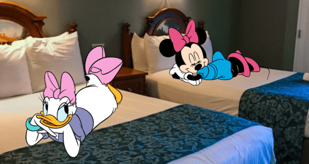 Daisy Duck and Minnie Mouse relax on separate beds inside a Disney Resort hotel room, smiling cheerfully with their heads resting on their arms, capturing the magical comfort of a Disney vacation.