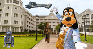 Goofy strikes a playful pose in front of the Galactic Starcruiser hotel, joined by R2-D2 and Chewbacca, with Star Wars spaceships soaring above—capturing the thrilling energy of a visit to this epic Disney experience.
