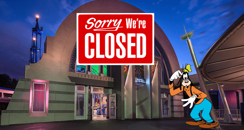 A "Sorry We're Closed" sign is displayed above Pluto, who greets guests at the entrance of Tomorrowland Light & Power Co. in Magic Kingdom during nighttime.