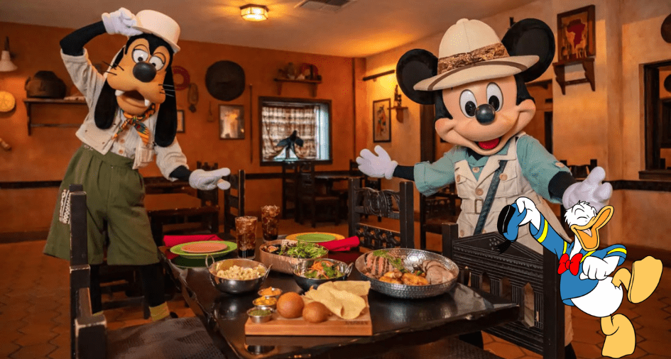 Mickey, Goofy, and Donald, dressed in safari gear, strike a fun pose by a feast of international dishes inside the lively African-inspired Tusker House Restaurant at Disney’s Animal Kingdom.