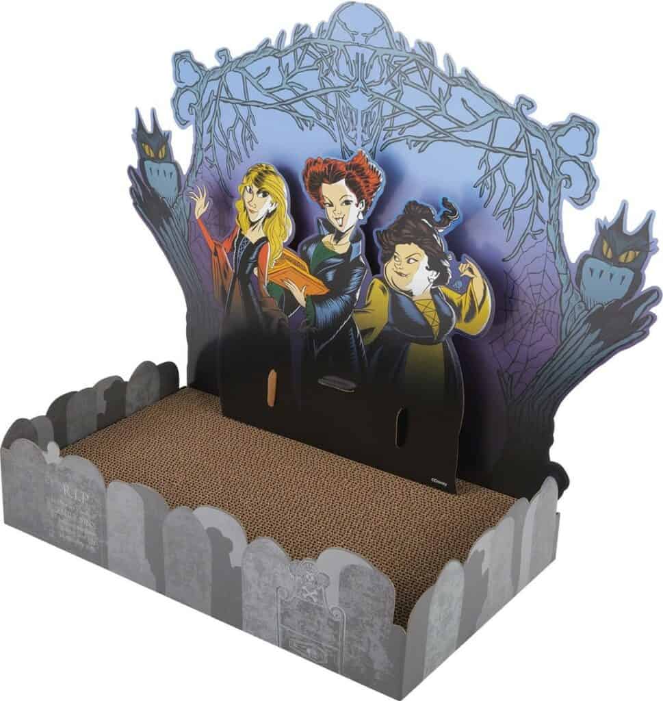 Hocus Pocus-themed cardboard cat scratcher styled like a whimsical prop from a haunted attraction, showcasing three playful cartoon witches amid gravestones and spooky décor—an enchanting treat for themed entertainment fans and collectors.